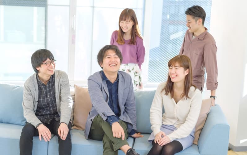 社員の写真。男性3名女性2名がにこやかに語らっている